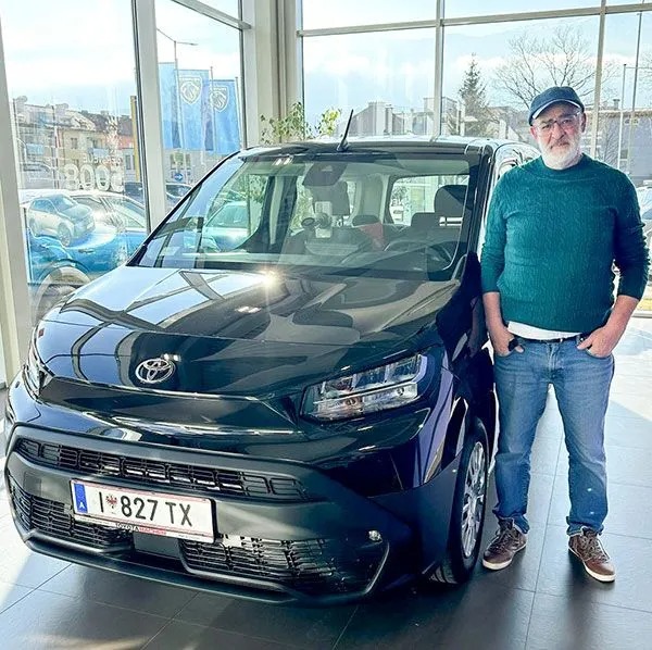 Mann steht neben schwarzem Auto